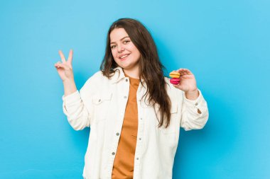 Makaronlar tutan, neşeli ve kaygısız genç kadın parmaklarıyla barış sembolü gösteriyor..