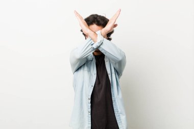 Beyaz arka planda genç yakışıklı bir adam iki kolu çapraz tutuyor, inkar kavramı.