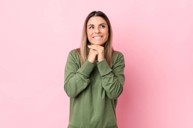 Kafkasyalı genç bir kadın yalnız, elleri çenesinin altında, mutlu bir şekilde yan tarafa bakıyor..