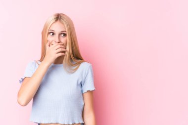 Pembe arka planda genç sarışın bir kadın. Bir fotokopi odasına dikkatlice bakıyor. Ağzını eliyle kapatıyor..