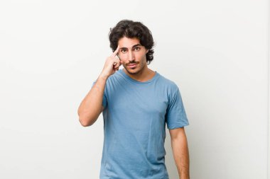 Beyaz arka planda genç yakışıklı bir adam parmağıyla tapınağı işaret ediyor, düşünüyor ve bir göreve odaklanıyor..