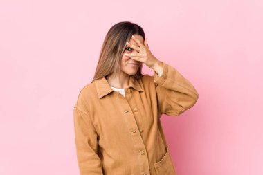 Genç beyaz kadın kameraya parmaklarıyla göz kırpıyor, yüzünü kapatmaktan utanıyor..