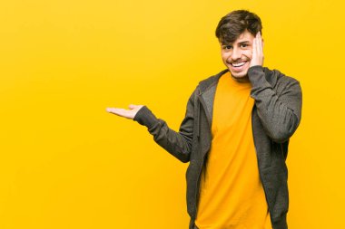 Genç İspanyol rahat adam bir avuç üzerinde kopya alanı tutar, yanak üzerinde el tutmak. Şaşırmış ve memnun.