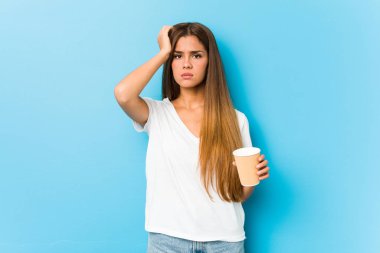 Young pretty caucasian woman holding a takeaway coffee being shocked, she has remembered important meeting.