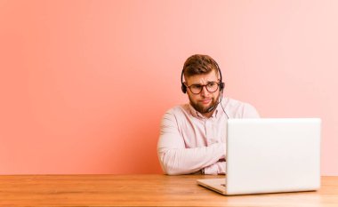 Çağrı merkezinde çalışan genç adam kameraya alaycı bir ifadeyle bakıyor..