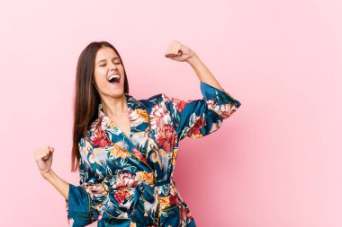 Kimono pijama giyen beyaz bir kadın zaferden sonra yumruğunu kaldırıyor..