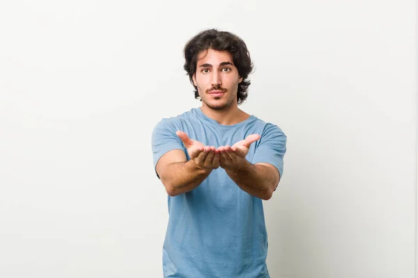 Jovem Homem Bonito Contra Fundo Branco Segurando Algo Com Palmas — Fotografia de Stock