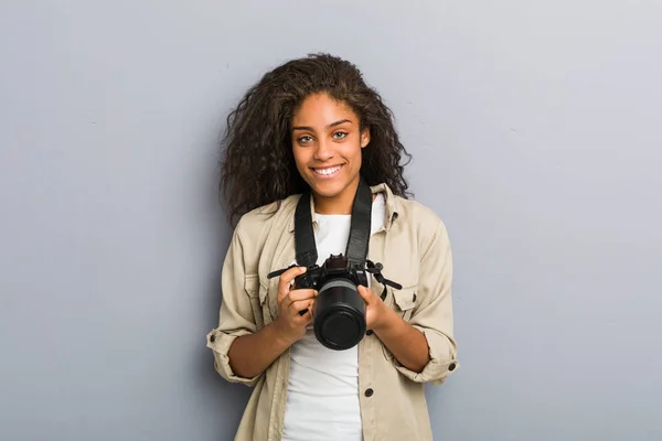 若いアフリカ系アメリカ人の写真家の女性がカメラを持って幸せ 笑顔と陽気 — ストック写真