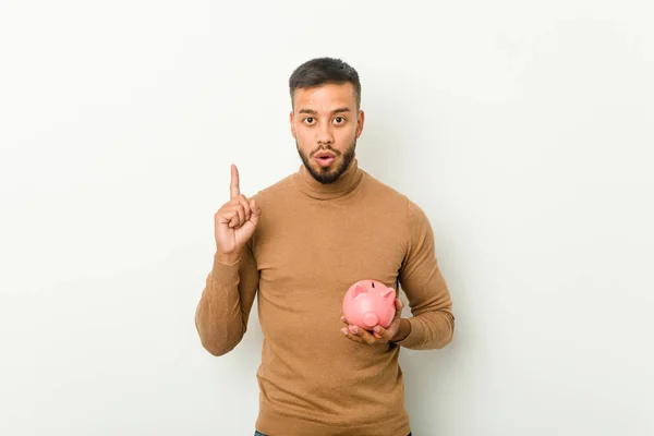 Joven Hombre Sudasiático Sosteniendo Una Alcancía Teniendo Alguna Gran Idea —  Fotos de Stock