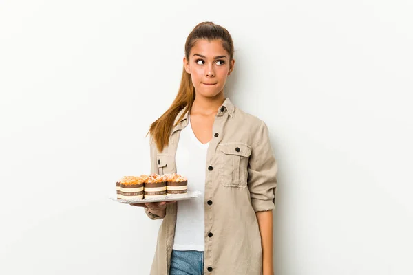 Young Caucasian Woman Holding Sweet Cakes Confused Feels Doubtful Unsure — ストック写真