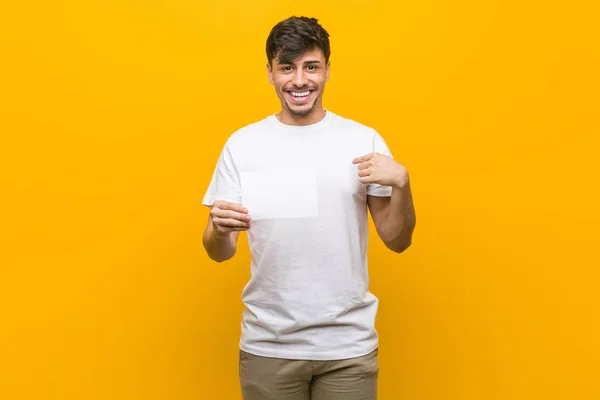 Young Hispanic Man Holding Placard Surprised Pointing Himself Smiling Broadly — Stock Photo, Image