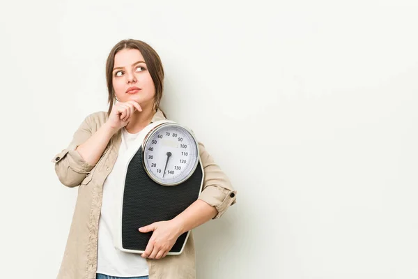 Jonge Bochtige Vrouw Houdt Een Schaal Kijken Zijwaarts Met Twijfelachtige — Stockfoto