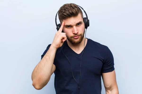 Joven Hombre Caucásico Escuchando Música Apuntando Templo Con Dedo Pensando — Foto de Stock