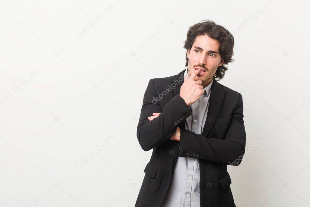 Young business man against a white background relaxed thinking about something looking at a copy space.