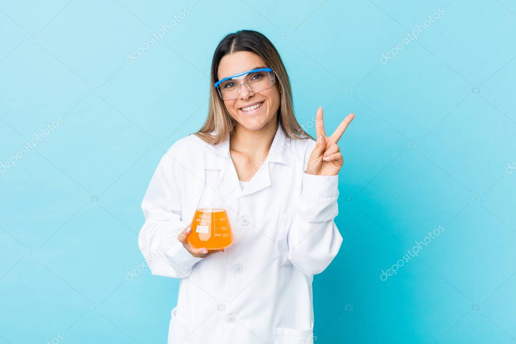 Young scientific woman joyful and carefree showing a peace symbol with fingers.