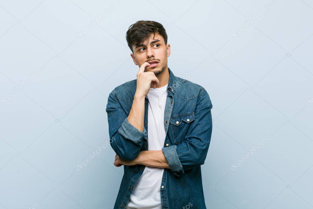 Young hispanic cool man relaxed thinking about something looking at a copy space.