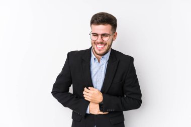Beyaz arka planda poz veren beyaz tenli genç beyaz iş adamı Kafkasyalı genç iş adamı mutlu bir şekilde gülüyor ve ellerini karnının üstünde tutarken eğleniyor..