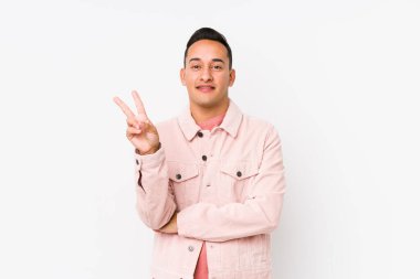 Genç Latin adam yalnız poz veriyor. İki numarayı parmaklarıyla gösteriyor..