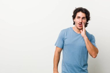 Beyaz arka planda genç ve yakışıklı bir adam gizli bir sıcak fren haberi veriyor ve yana bakıyor.