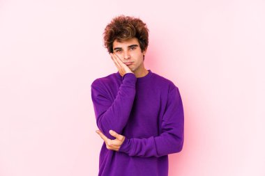 Pembe arka planda yalnız, sıkılmış, yorgun ve dinlenmeye ihtiyacı olan genç beyaz bir adam..