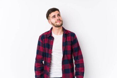 Beyaz arka planda poz veren genç beyaz bir adam hedeflerine ve amaçlarına ulaşma hayali kuruyor.