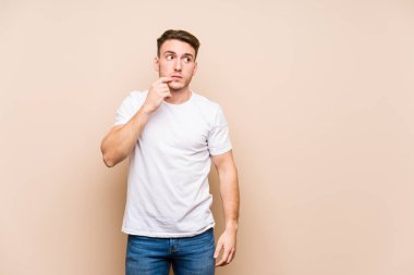 Kafkasyalı genç adam izole edilmiş poz veriyor. Rahatlamış bir şekilde bir şeyin fotokopi odasına baktığını düşünüyor..