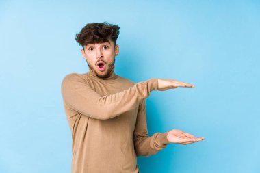 Genç Arap adam şok olmuş ve hayrete düşmüş. Ellerinin arasında bir kopya alanı tutuyor..