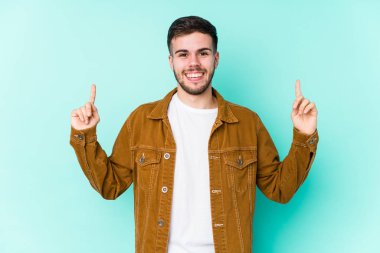 Genç ve yakışıklı bir adam iki elini de havaya kaldırarak boş bir alan gösteriyor..