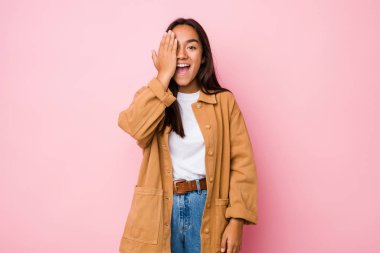 Genç melez Hintli kadın izole edilmiş. Yüzünün yarısını avuç içiyle kaplayarak eğleniyor..