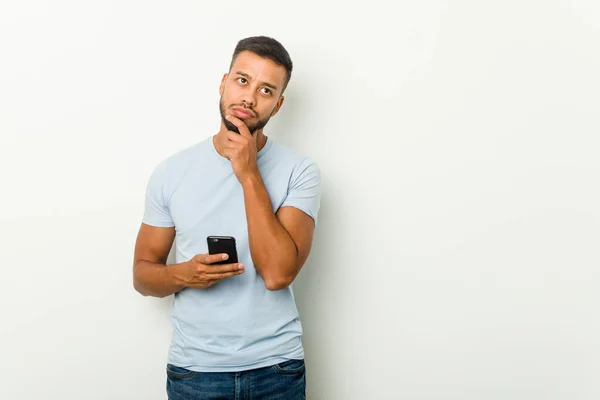 Young Mixed Race Asian Man Holding Phone Relaxed Thinking Something — Stock Photo, Image