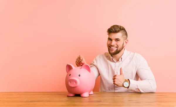 Young Caucasian Man Sitting Piggy Bank Smiling Raising Thumb — 스톡 사진