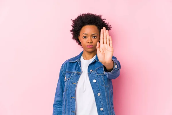 年轻的非洲裔美国女人面对着一个粉色的背脊孤立地站着 伸出的手显示出停止的迹象 阻止了你 — 图库照片
