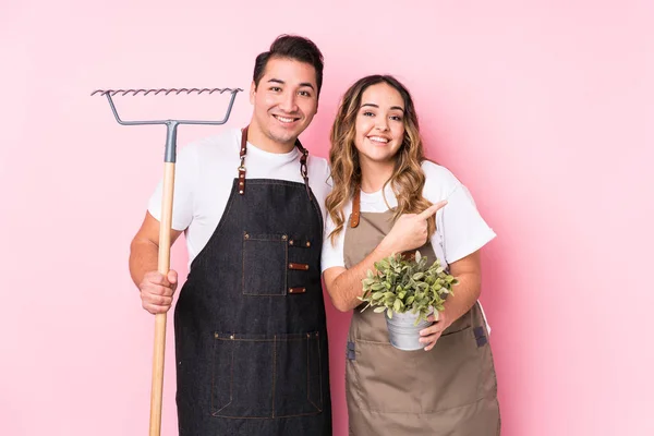 Jonge Paar Tuinman Geïsoleerd Glimlachen Wijzen Opzij Iets Laten Zien — Stockfoto