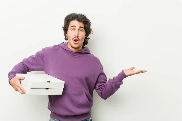 Joven Sosteniendo Paquete Pizzas Impresionado Sosteniendo Espacio Copia Palma —  Fotos de Stock