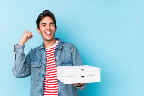 Joven Caucásico Sosteniendo Pizzas Aisladas Levantando Puño Después Una Victoria — Foto de Stock
