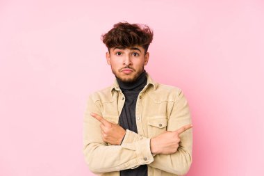 Arka planda yalıtılmış noktalarda poz veren genç bir Arap, iki seçenek arasında seçim yapmaya çalışıyor.