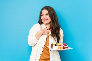 Genç, kıvrımlı bir kadın elinde tatlı bir pasta tutarken kahkahalar atıyor..