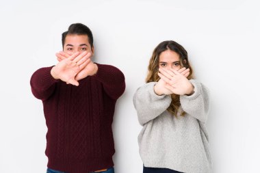 Beyaz arka planda poz veren genç bir çift inkâr jesti yapıyor.