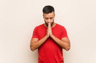 Güney Asyalı genç adam, el ele tutuşup, ağzının kenarında dua ediyor, kendinden emin..