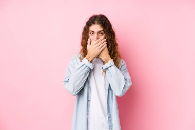 Uzun saçlı adam yalnız poz veriyor. Ağzını elleriyle kapatıyor..