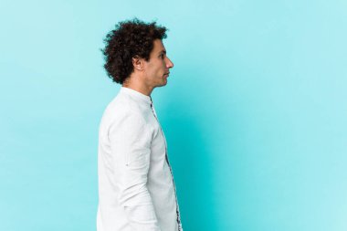 Genç, kıvırcık, olgun, zarif bir gömlek giyen, sola bakan, yan pozlar veren bir adam..