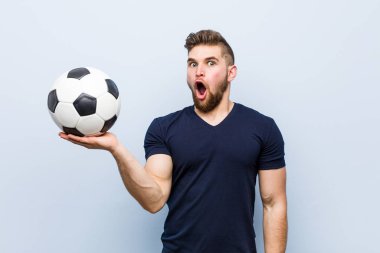 Bir futbol topu tutan genç kafkas adam avuç içinde kopya alanı tutarak etkilendim.