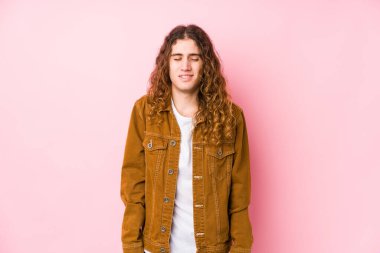 Genç, uzun saçlı adam yalnız gülüyor ve gözlerini kapatıyor, rahatlamış ve mutlu hissediyor..