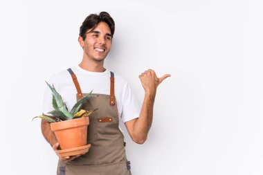 Kafkasyalı genç bahçıvan bir bitkiyi elinde tutuyor. Başparmak uzakta, gülerek ve kaygısızca..