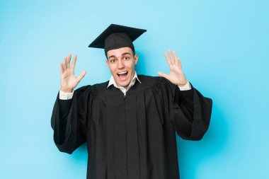 Genç beyaz adam zaferi ya da başarıyı kutlayarak mezun oldu.