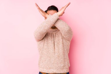 Pembe arka planda poz veren kıvrımlı genç adam iki kolu çapraz tutuyor, inkar kavramını koruyor..