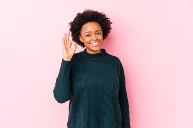 Orta yaşlı Afrikalı Amerikalı kadın pembe arka planda yalnız, neşeli ve kendinden emin..