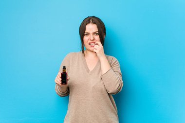 Buharlaştırıcı tutan, tırnaklarını yiyen, gergin ve endişeli bir kadın..