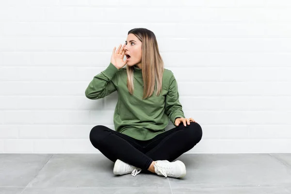 Jovem Caucasiana Sentada Chão Gritando Segurando Palma Perto Boca Aberta — Fotografia de Stock