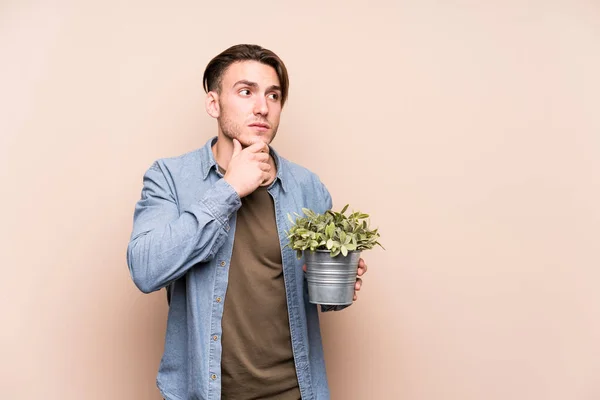 Junger Kaukasischer Mann Der Eine Pflanze Mit Zweifelndem Und Skeptischem — Stockfoto